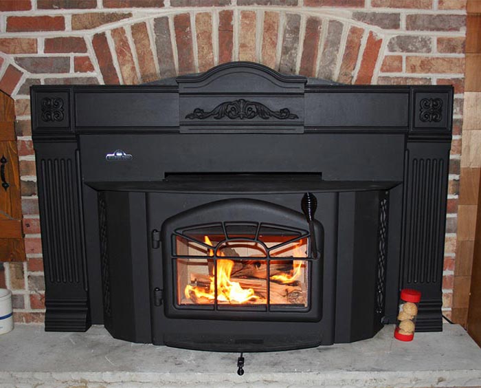 black wood burning stove insert set in a brick surround with a stone hearth