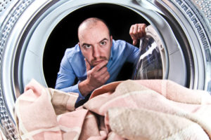 man looking curiously into clothing dryer