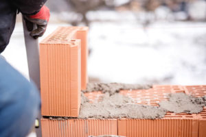 hands repairing masonry square