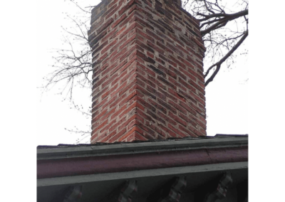 Close up of brick chimney with visible wear and damage to masonry, crown and caps