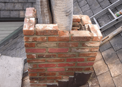 Chimney repair in progress with damaged masonry removed and new liner exposed
